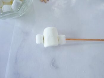 showing bamboo skewer with mini marshmallow, regular size marshmallow and another mini marshmallow on bamboo skewer. 