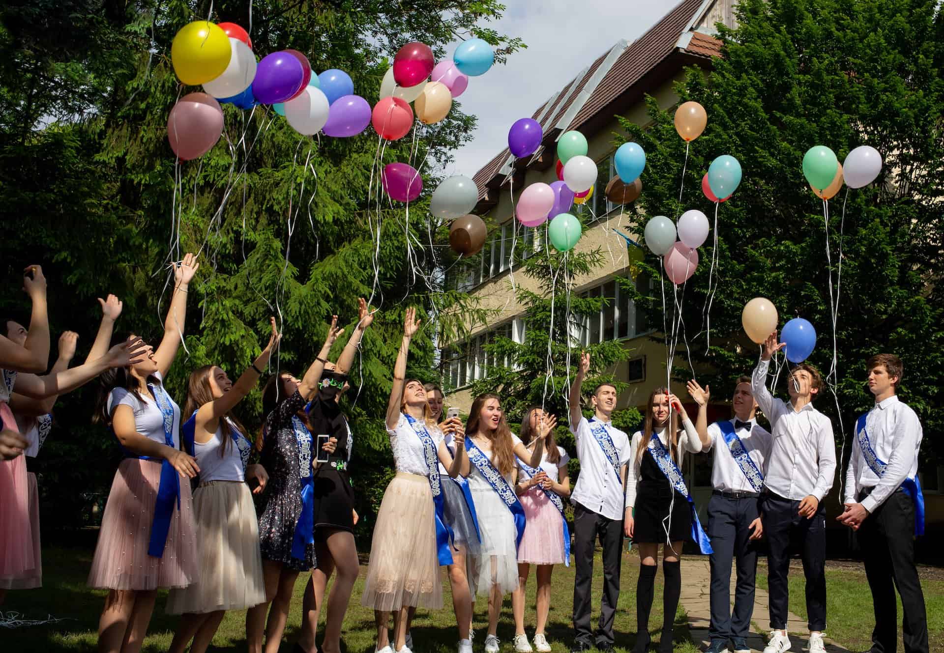 Group of graduates having fun at their graduation party by releasing balloons