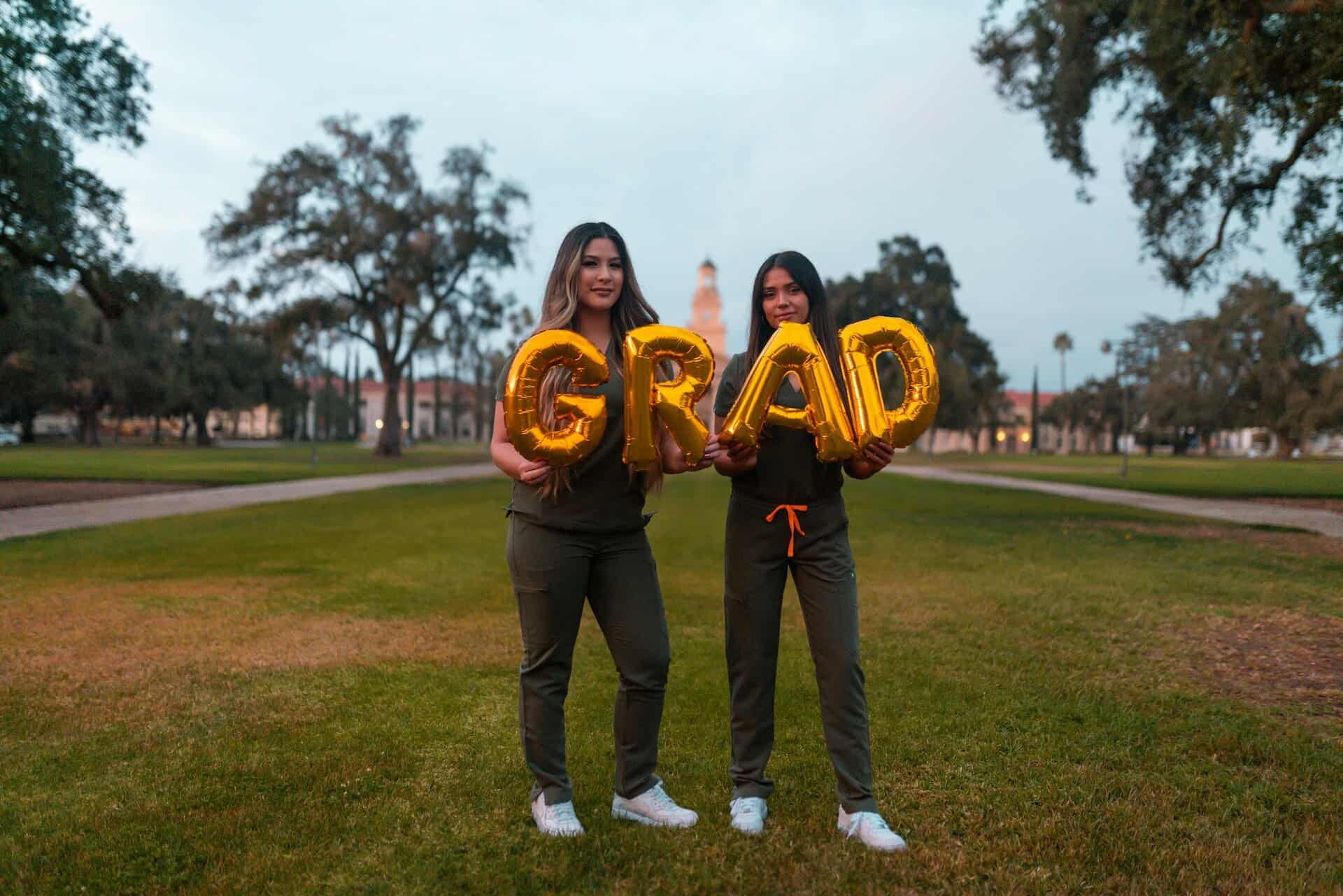 Two friends holding grad balloons