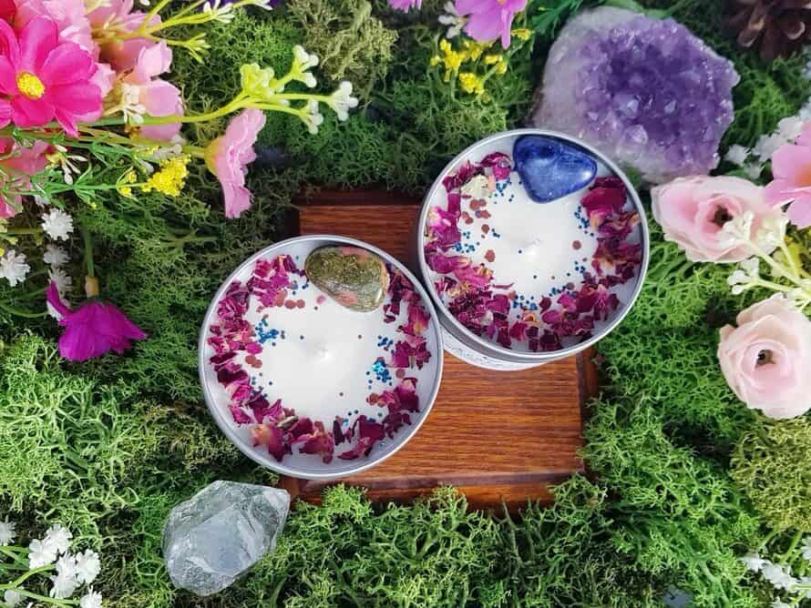 Above view of two astrology crystal candles with rocks and flowers in them and surrounding them.
