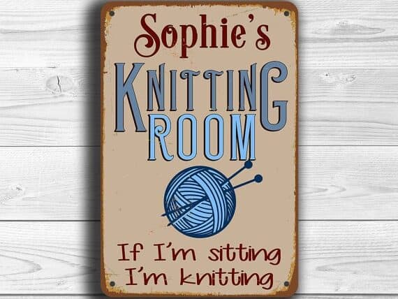 Custom wooden sign with red font that say's Sophie's then blue font that says Knitting room with a blue yarn ball. 