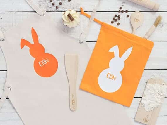 White apron with an orange Easter bunny on it with white font that says ERIN and an orange bag with a white bunny with orange font that says ERIN.