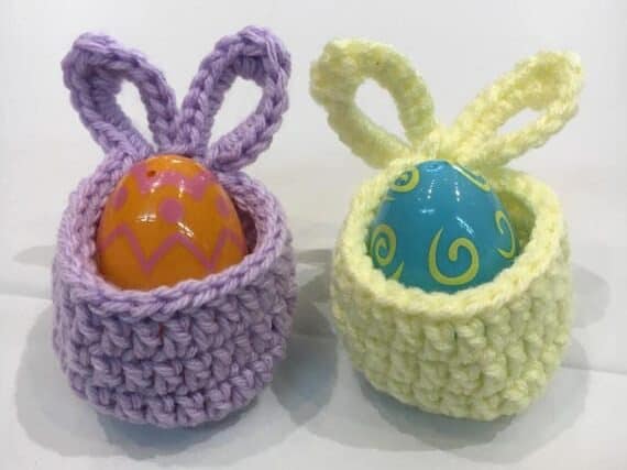 Crocheted purple and yellow basket with bunny ears as a handle both with a mini Easter egg in it.