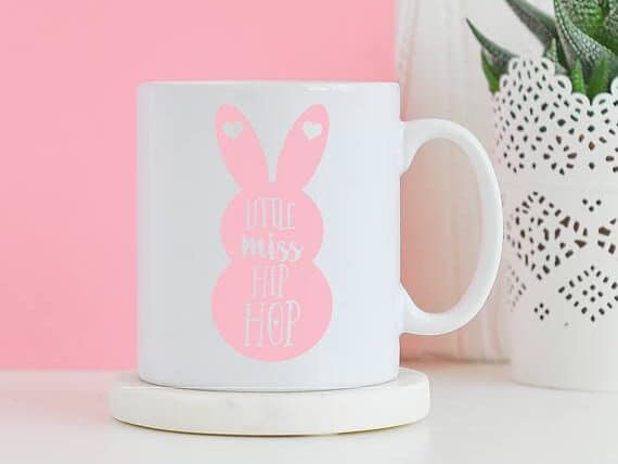 White coffee mug with a pink bunny on it with white font that says Little Miss Hip Hop.