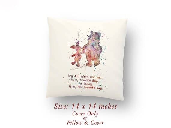 White square pillow with water colored Winnie the pooh holding piglets hand with writing below. 