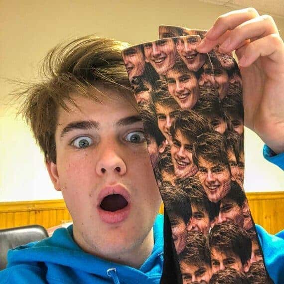 Shocked boy holds up a pair of socks with his face all over them. 