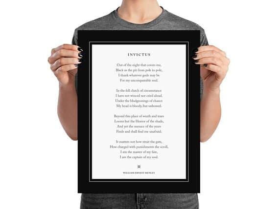 Person holding a black frame with a poem in it. 