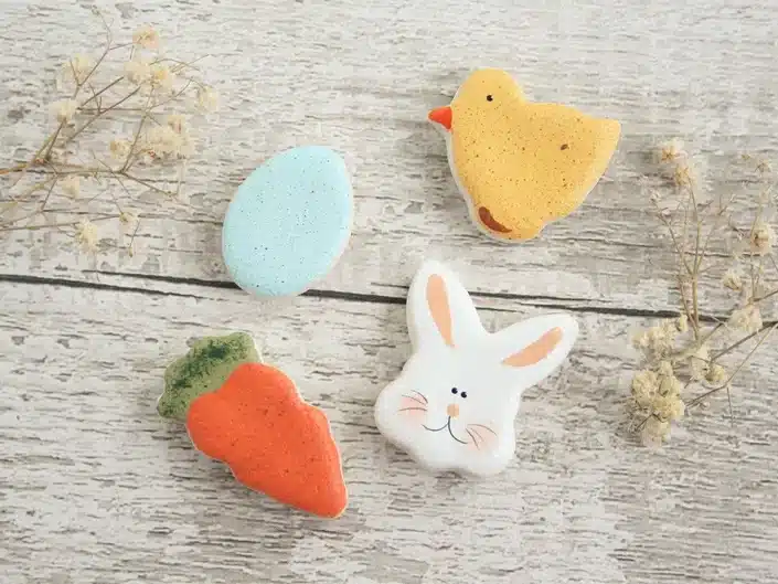 Four salt dough magnets, one an orange carrot, blue egg, yellow chick, and a white bunny head. 