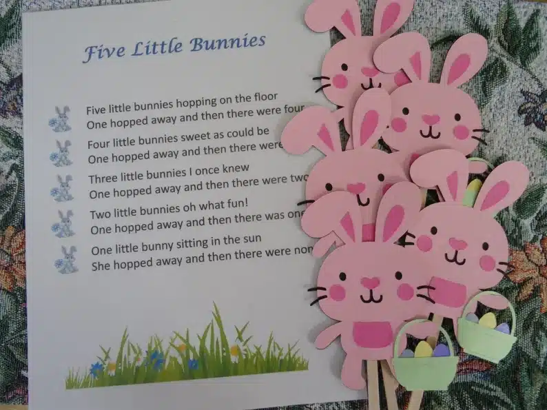 White paper with Five little bunnies song written on it with 5 pink bunnies holding Easter eggs beside it. 