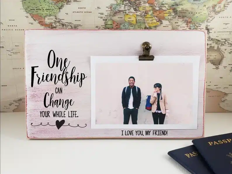 Photo frame with a clip showing a photo of two friends together, black font on that side that says 