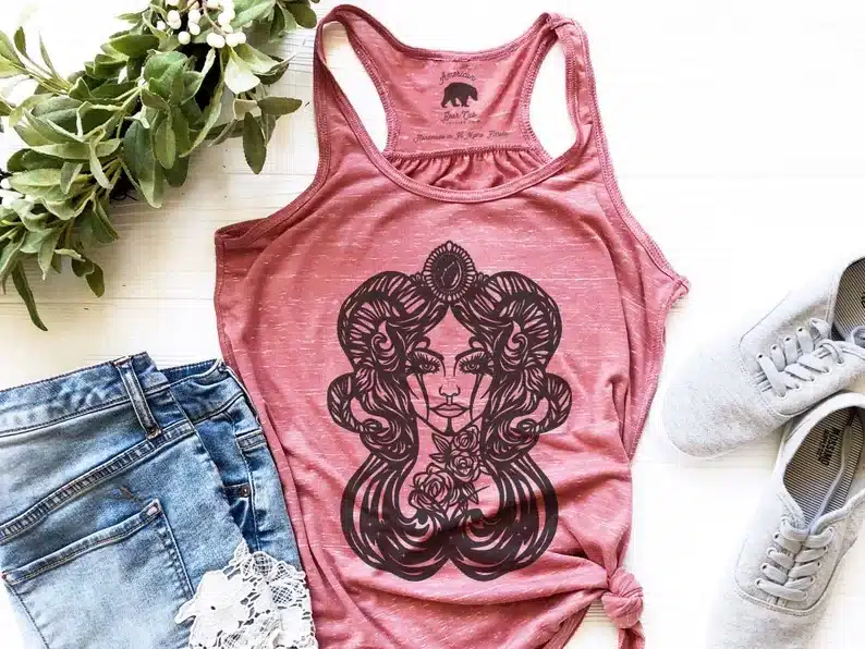 Pink tank top with black print of a woman with ram horns. 