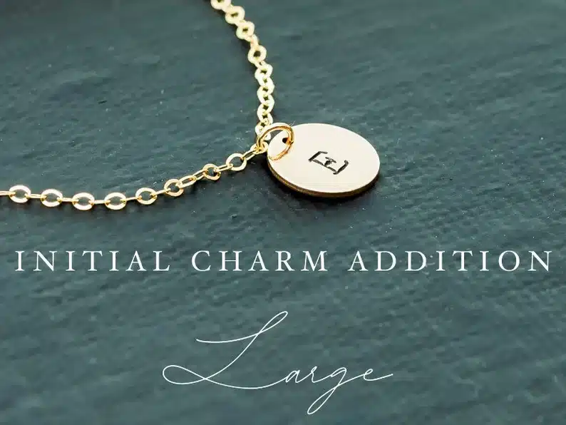 Gold chain with a round charm that has an engraved E on it. 