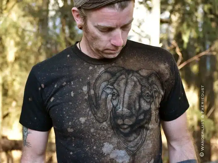 Man wearing a black t-shirt with a Rams head on it with splattered marks all over it. 