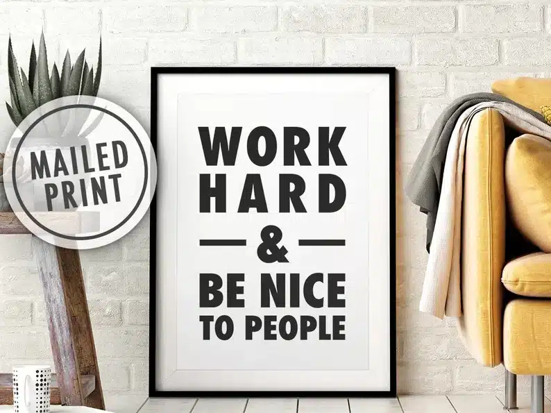 White sign with a black frame and black font that says WORK HARD & BE NICE TO PEOPLE. 