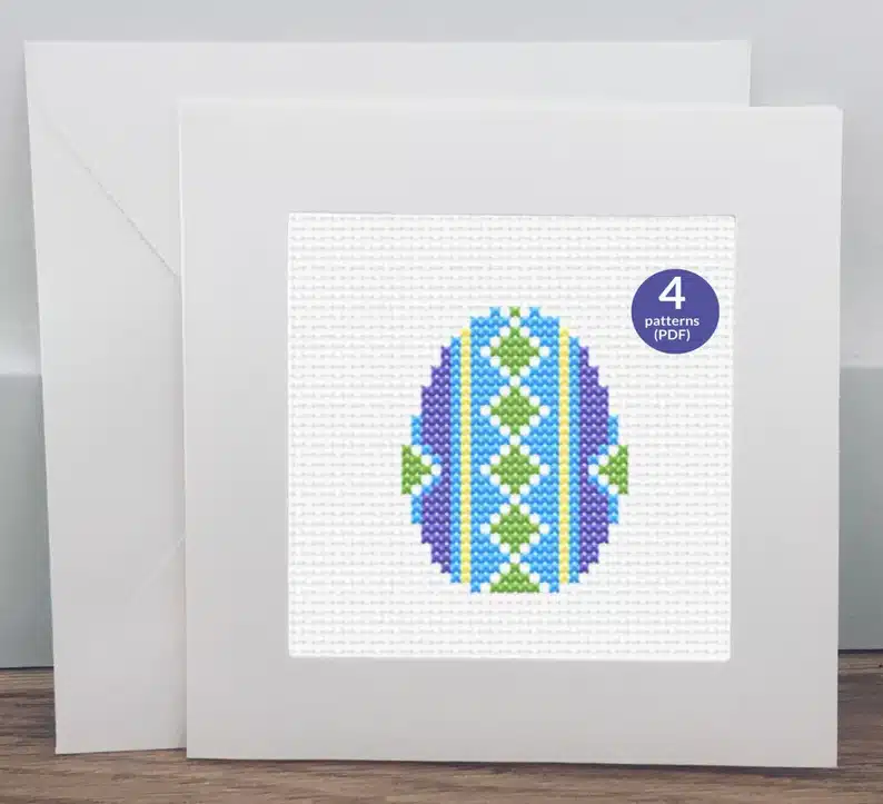 Cross stich material made into a card with a green, purple, teal, and yellow Easter egg on it. 
