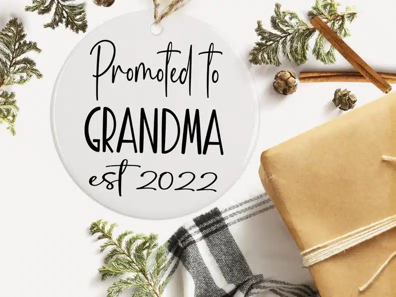 Round white ornament with black font that says promoted to grandma est 2022. 