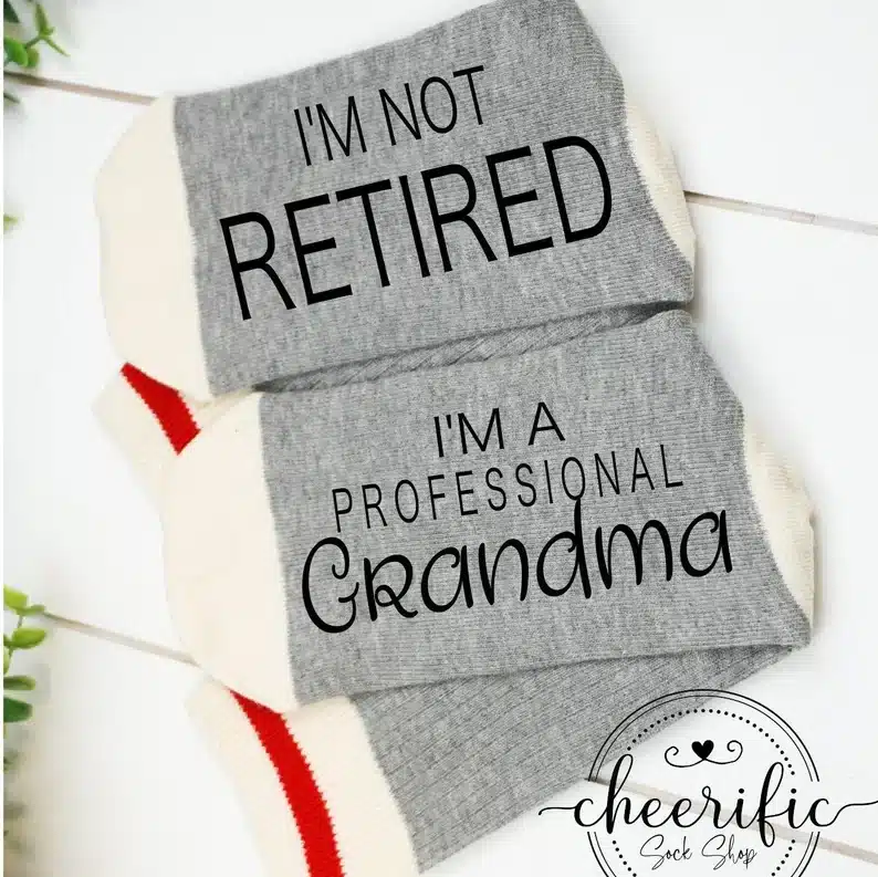Grey socks with black font that says "I'm not retired" on one and "I'm a professional grandma" on the other. 