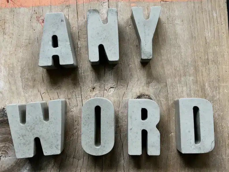 Wooden background with concrete letters that spell ANY WORD 