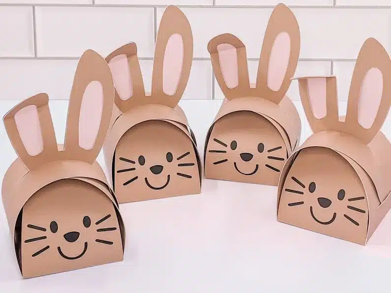 Four brown paper treat boxes of bunny heads with black smiling faces. 