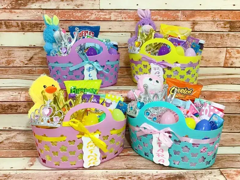 Four premade Easter baskets, purple, yellow, pink, and blue with names attached on them. all filled with chocolates, plastic eggs, plush animals. 