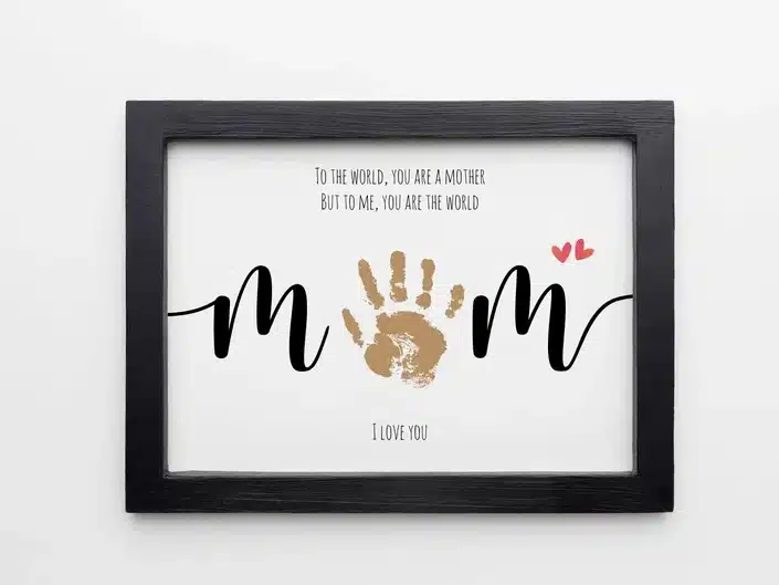 Best Mother's Day Gifts from Babies: Dark wood rectangle frame with black font that says to the world you are a mother but to me you are the world. below an m with a brown handprint as an o and another m beside it. I love you wrriten below. 