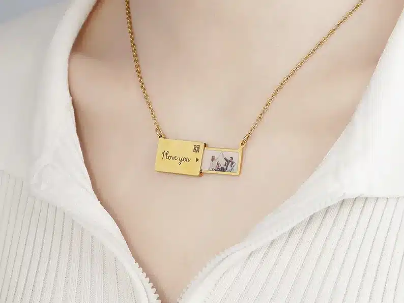 Gold rectangle envelop charmed necklace with photo being pulled out of envelop charm. 
