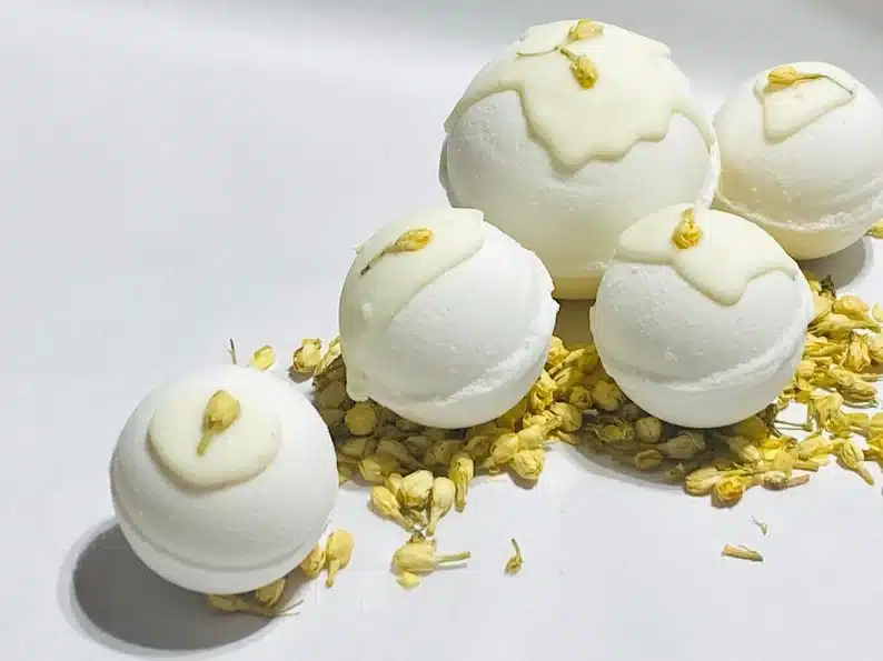 Five cocoa butter cashmere bath bombs, all white with gold on them. 