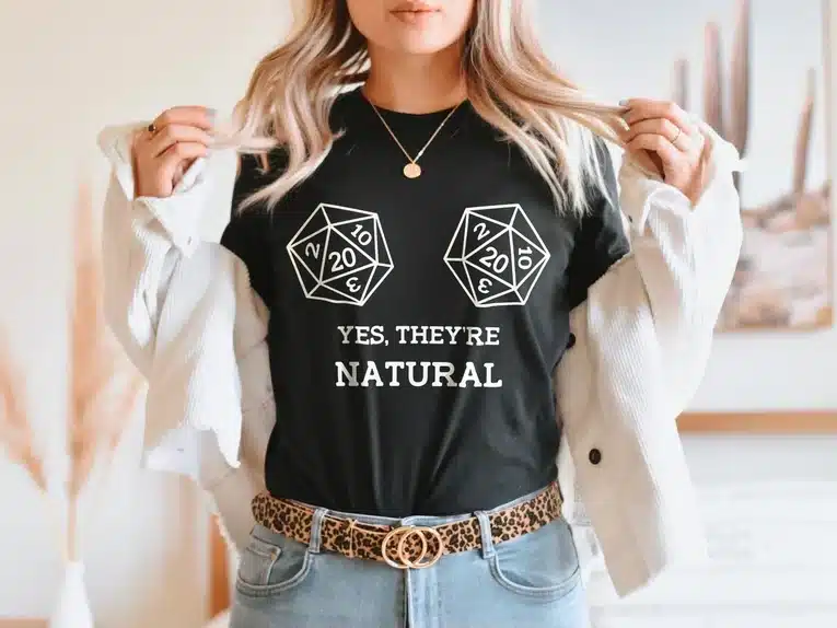 Woman wearing a black t-shirt with white fonr that shows two D&D dice and says Yes, they're natural. 