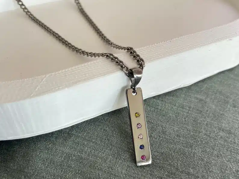Silver necklace with a long rectangle charm with five different birthstones on it. 