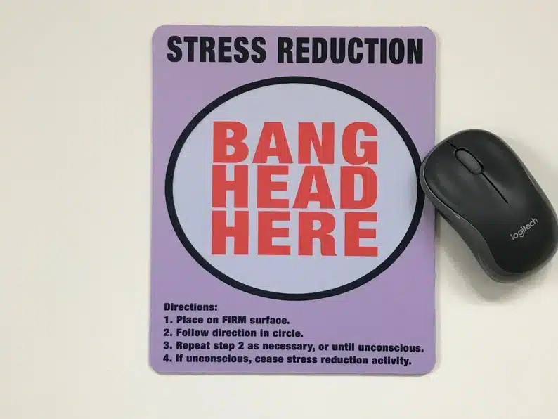 Square lavendar colored mousepad with black font that says Stress reduction with red font below that says Bang head here. with a black mouse beside it. 