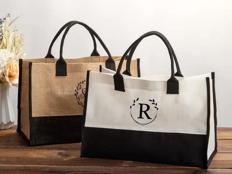 Two burlap tote bags one brown with black writing on it and one white and black with a black R on it. 