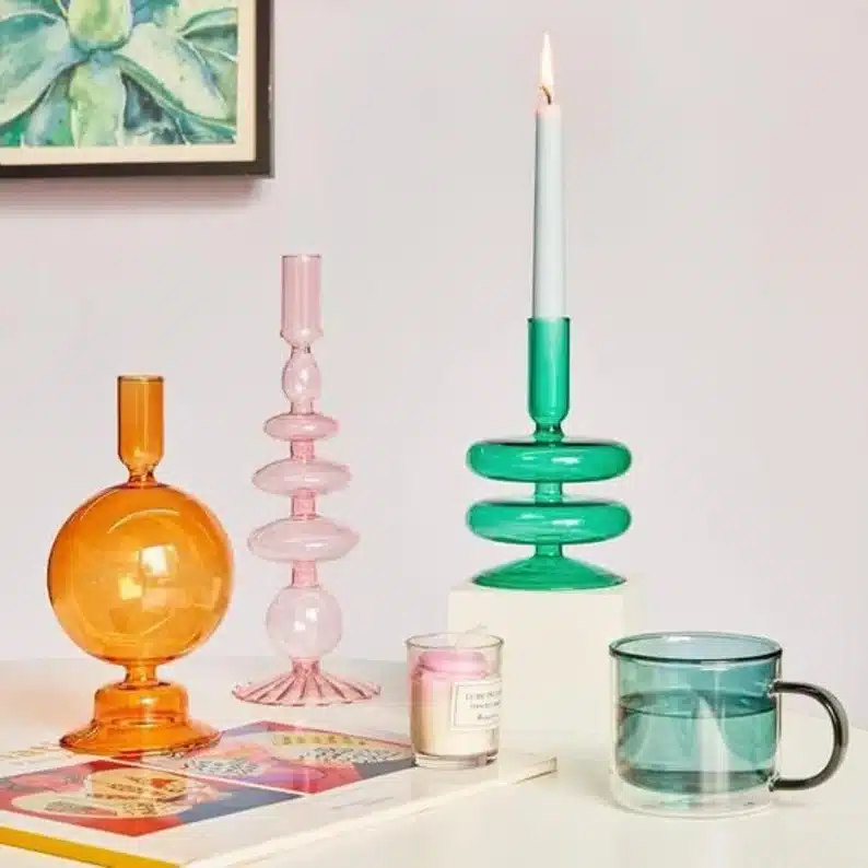Colorful glass candle holders, all different shapes and sizes. orange, light pink, green, and blue shown. 