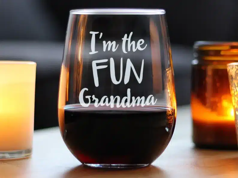 Clear stemless wine glass with white font that says "I'm the fun grandma" 