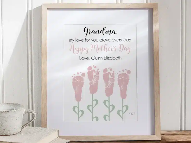 Bronze frame with black font that says Grandma my love for you grows every day. Happy mothers day love Quinn Elizabeth. With four pink footprints made into flowers. 
