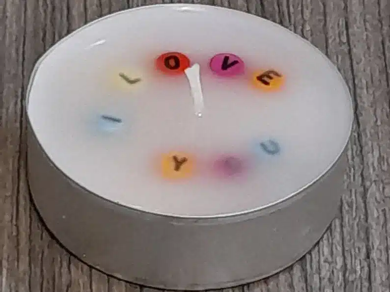 Hidden message candle, white candle with beads that say I LOVE YOU, all different colored beads. 