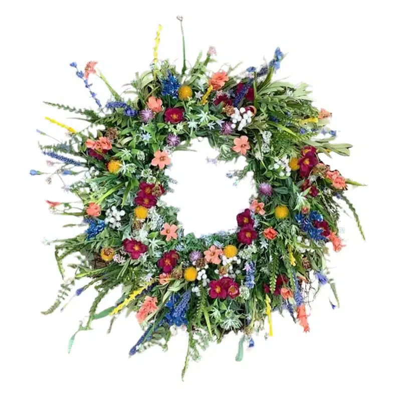 Spring wreath with various greens, colorful flowers, and some eggs all around it. 