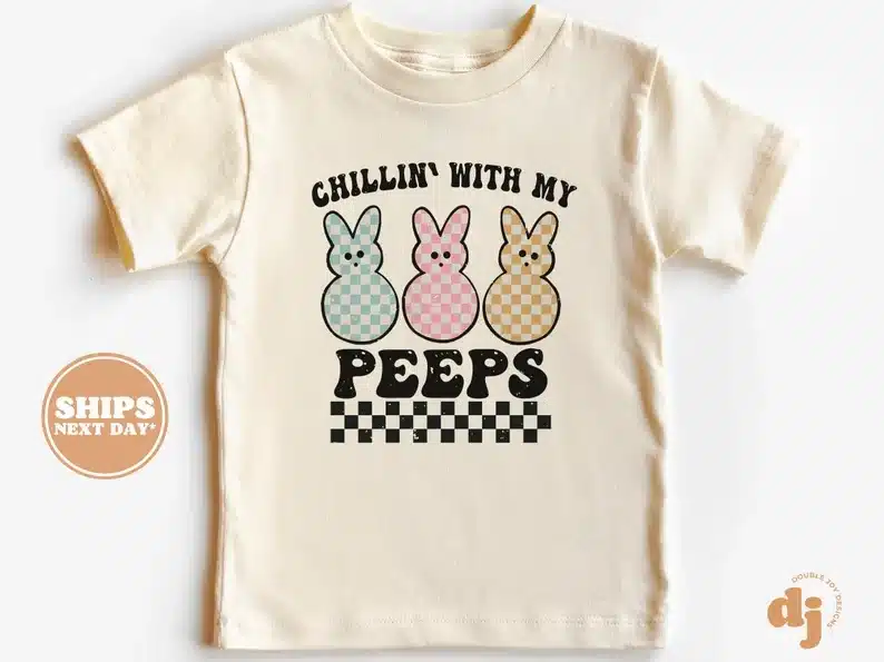 Cream t-shirt that says in black font chillin' with my peeps and three peeps shown on shirt; blue, pink, and yellow. 