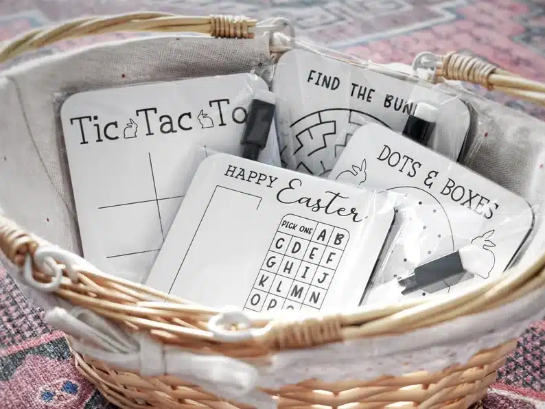Basket full of mini dry erase boards that have various Easter games on them with a white board marker attached. 