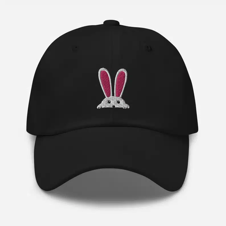 Easter Gifts for Diabetics: Black baseball cap with a white bunny peaking over the brim with pink ears. 