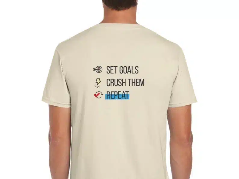 Back of a white tshirt that says set goals, crush them, and repeat. 
