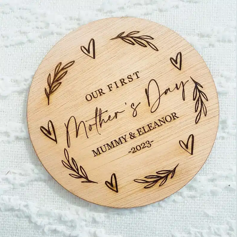 Round wooden sign engraved with hearts and font that says our first mother's day mummy & Eleanor 2023 