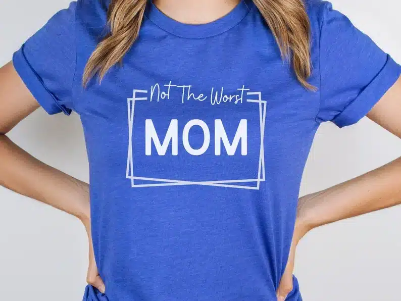 Women wearing a blue t-shirt with white font that reads Not the worst MOM. 
