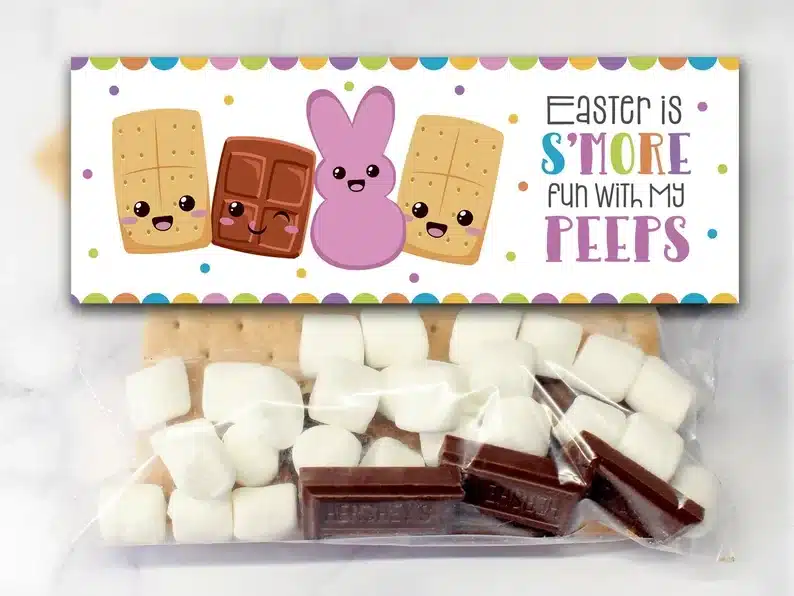 Clear baggy filled with mini marshmallows, chocolate pieces, and graham crackers with a label on the top that says Easter is S'more fun with my peeps and cute cartoon graham cracker, chocolate and purple bunny peep beside it. 