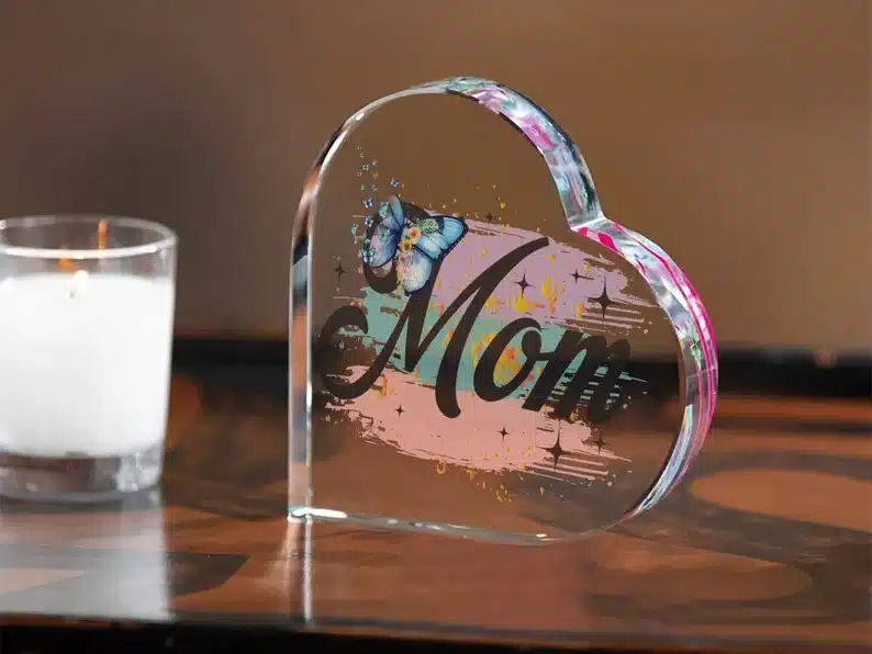 Clear acrylic heart that says MOM with a blue butterfly on it. 