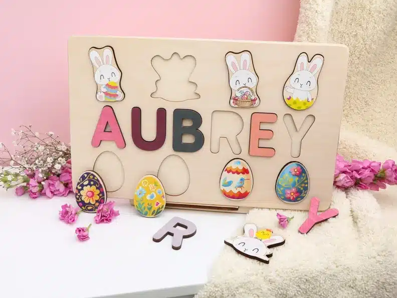 Wooden name puzzle with removable name letters, four bunnies above it and 4 eggs below it. 
