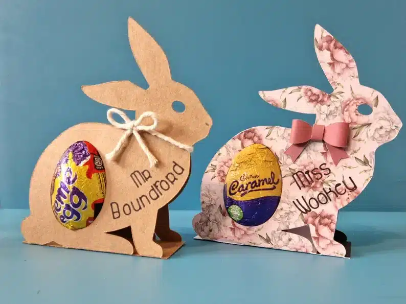 Paper bunnies made to be 3D to hold a chocolate Easter egg, one brown and one pink. 