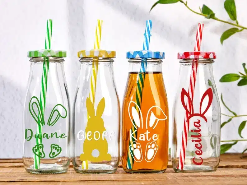 Four clear drink bottles with kids names on it with a bunny. 