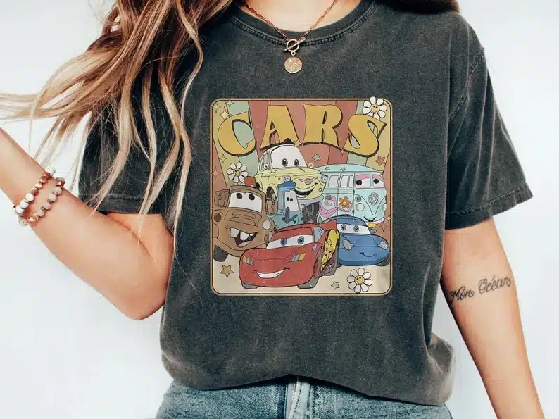 Woman wearing a dark grey t-shirt with CARS and some characters shown on it. 