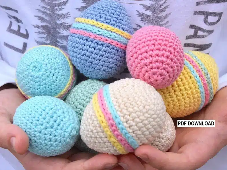Person holding various colored crocheted Easter eggs. 