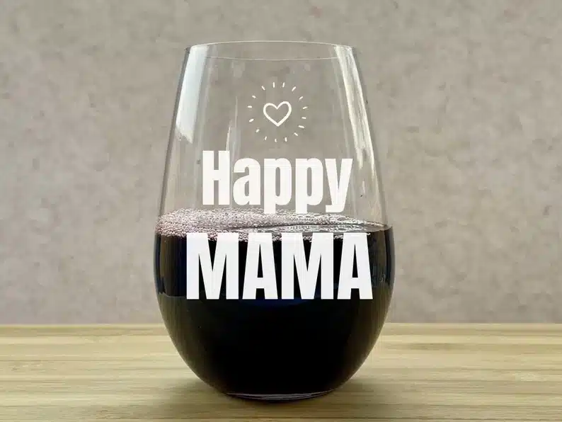 Clear stemless wine glass with white font that says Happy MAMA. 